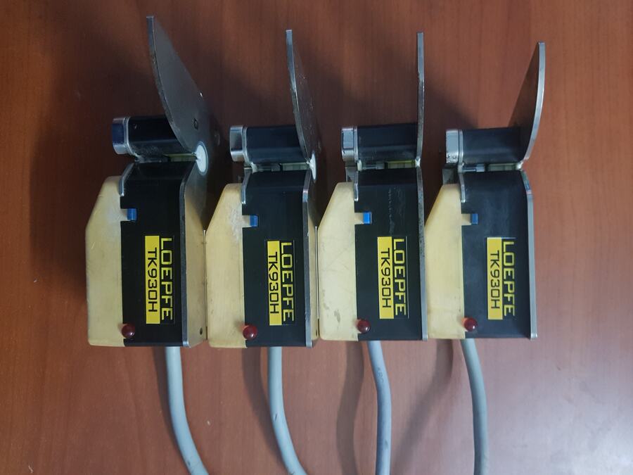 Four yellow yarn clearer measuring heads with cables standing on a workbench